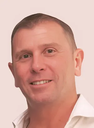 Homme souriant en chemise blanche sur fond beige.