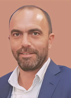 Homme souriant en costume bleu sur fond beige.