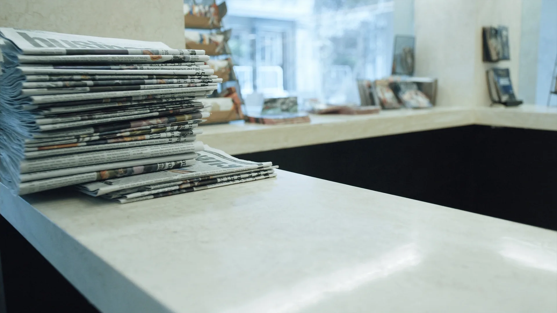 Hotel news kiosk with stacks of fresh broadsheets and magazines, illustrating Perplexity's broad fresh citations