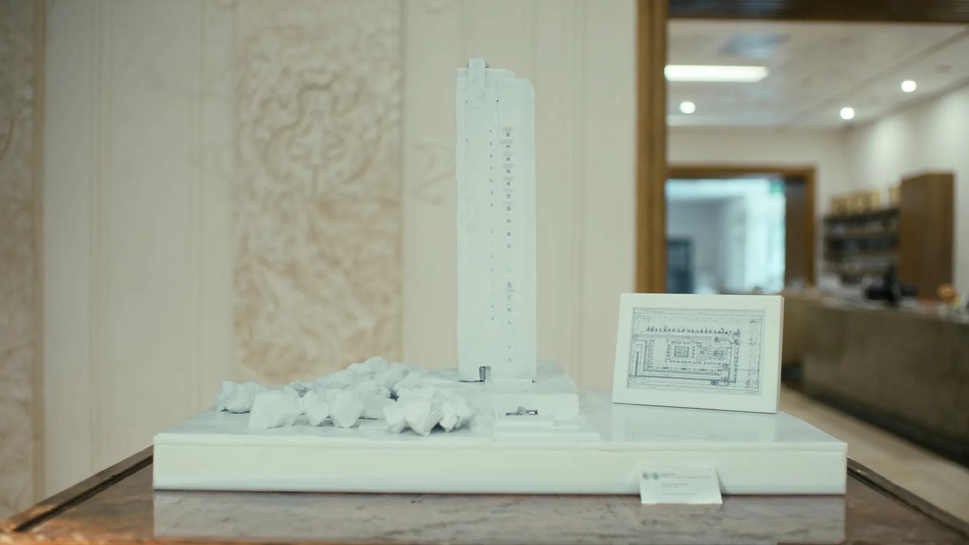 Architectural model on a polished plinth with a framed schema diagram beside, illustrating structured technical foundation