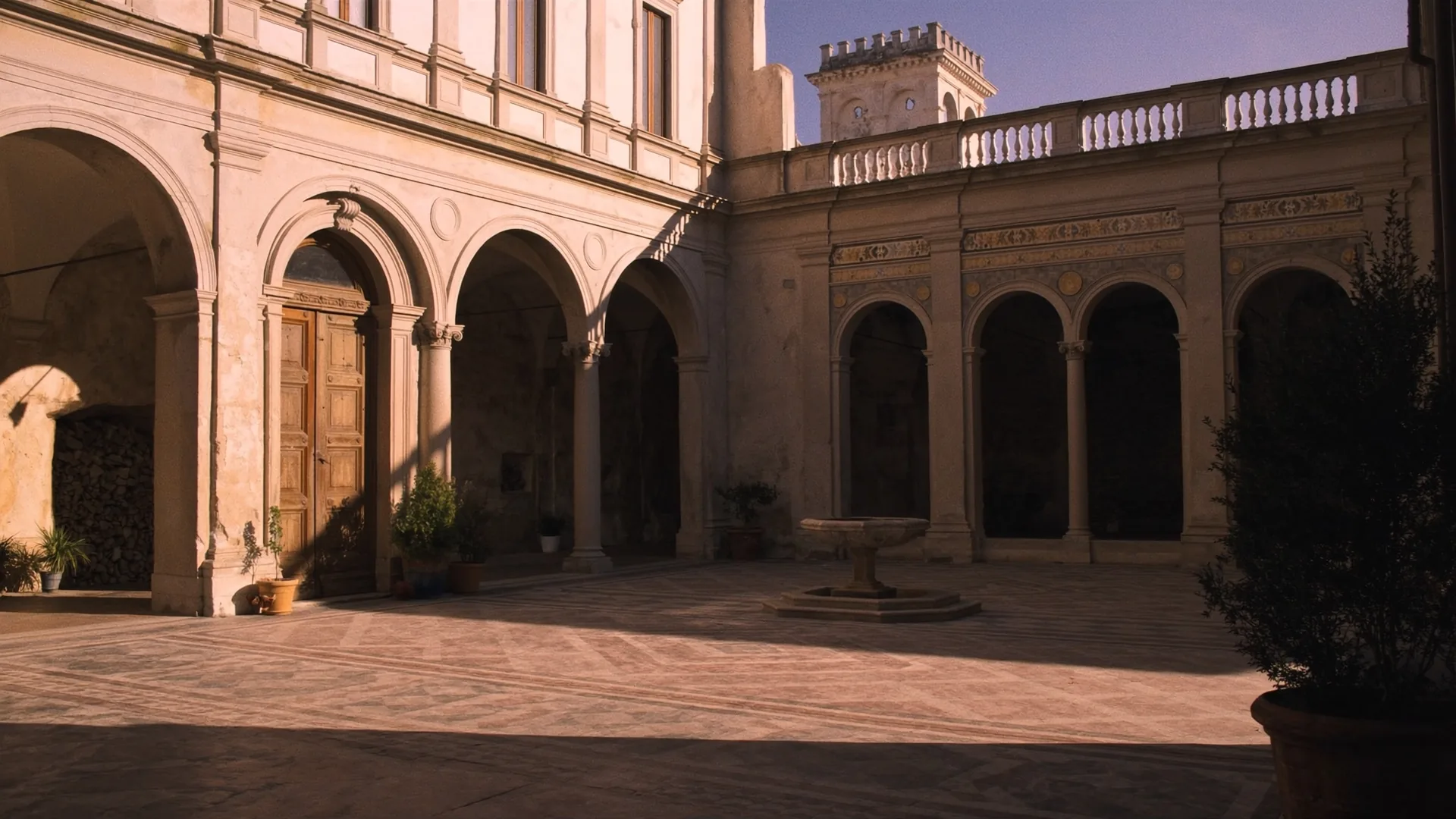 Interior courtyard of a restored stone palazzo with arched colonnades, warm terracotta tones, a small fountain, late afternoon light casting geometric shadows