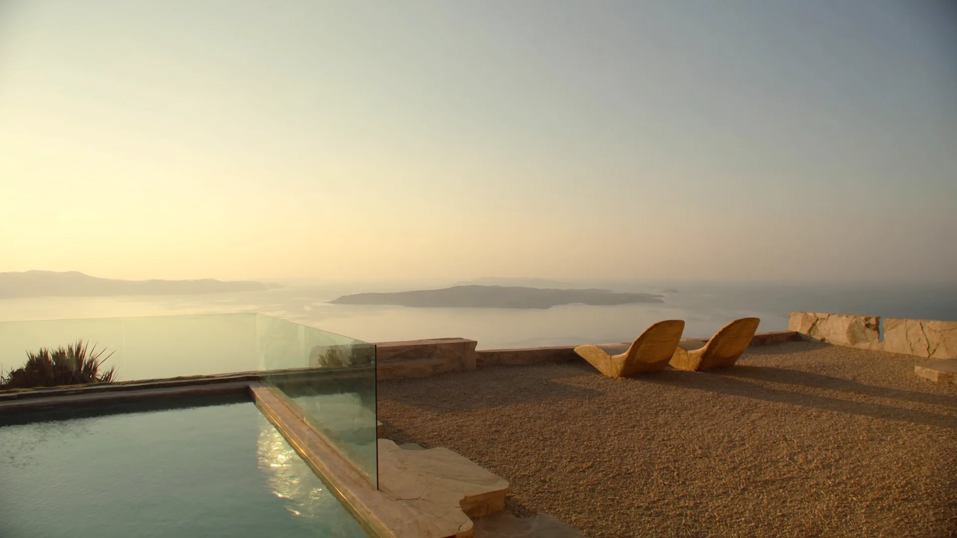Cliffside Mediterranean terrace with two lounge chairs overlooking the sea at golden hour, infinity pool in the foreground